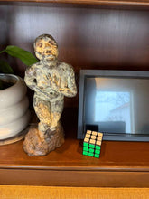 Cargar imagen en el visor de la galería, Bronze figure Statue and Rubik's Cube on a wooden surface with a plant and framed picture in the background.