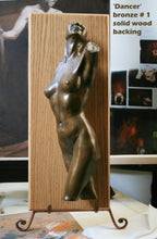 Load image into Gallery viewer, Bronze sculpture of a nude female dancer in a dynamic pose, mounted on a vertical wood panel with metal easel stands, shown indoors with text reading 'Dancer' bronze #1 solid wood backing.'.