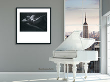Load image into Gallery viewer, PRint of reclining nude woman thinking is framed in a simple thin line black frame and a white mat.  The mat is clearly cut so that it has a lot of white space below the art with top and sides being equal but very different from the bottom.  Shown here hung in a City loft apartment room with a white piano.
