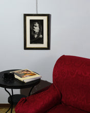 Carica l'immagine nel visualizzatore di Gallery, Red armchair in a room with a framed black and white picture on the wall and a small round table.