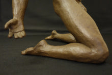 Load image into Gallery viewer, Close-up of a sculpted bronze figurine showing a kneeling human form with detailed muscular legs and hand, finished in a warm brown terracotta-like material against a dark background.