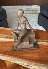 將圖片載入圖庫檢視器 Another view looking slightly downwards towards the small bronze figure sculpture of a seated young muscular bald man.  He and his granite tile base rest o a gorgeous wooden table.