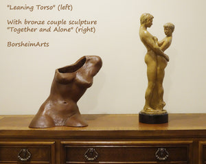 A medium-sized sculpture of a woman's torso in terra-cotta looks great next to the same artist's bronze sculpture of a standing, embracing couple, Together and Alone.