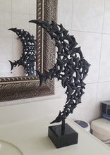 Load image into Gallery viewer, This flying bird sculpture rests on a bathroom countertoop and a part of it is reflected in the large mirror behind the sink.
