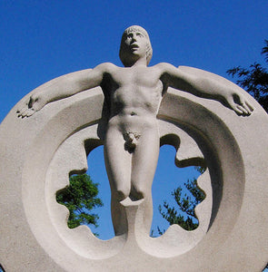 Detail of stone carving of standing man's naked body.  His arms are extended beside him, lying on a large circular shape.  Spaceman is a limestone carving sculpture by Vasily Fedorouk