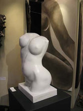 Load image into Gallery viewer, Here you may see how the top of the female marble torso follows the shape of an open book.  This is intentional by the artist sculptor Kelly Borsheim.  Shown here at her first, and last exhibit with a large female nude painting in the background. The work sold immediately.
