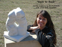 Load image into Gallery viewer, The female artist Kelly Borsheim with her newly completed marble carving of two human torsos Back to Back, Dripping Springs, Texas, at a sculpture show.