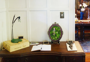 small to medium sized oil painting of botanical subjects may be hung on the wall or, as shown here, exhibited on a easel, such as the type made for collector plates. The two sculptures in the image are also by the same artist, Kelly Borsheim