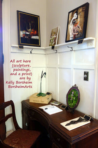 Three paintings, one framed print, and two sculptures make this entryway welcoming and warm home decorsmall to medium sized oil painting of botanical subjects may be hung on the wall or, as shown here, exhibited on a easel, such as the type made for collector plates. The two sculptures in the image are also by the same artist, Kelly Borsheim