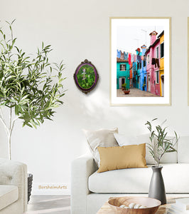 Mix and match types of art and images to make your home your happy place.  Shown here is a living room with the small oval botanical painting next to a larger photographic print of laundry hanging on the island of Burano, Italy... both by artist Kelly Borsheim