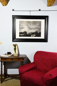 Original drawing Splash, crashing waves on dark rocks is shown hung on a wall in a country home, with the small bronze bas relief Ten, also available from artist Kelly Borsheim
