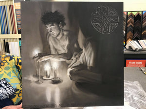 The male portion of the triptych oil painting Luminosity.. a shirtless man sits half reclining, resting on one arm.  the other reaches out to touch the fire of the candlelight.  Celtic symbology of peace and connectedness is shown painted in silver in the upper right corner of the artwork