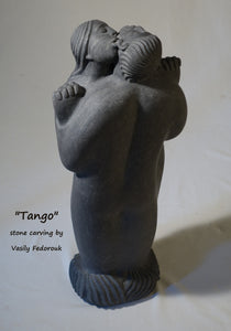 Tango a 2-foot tall stone carving in Alaskan marble of a closely dancing couple.  As he embraces her, she nibbles on his ear.  The figures are modern, abstracted or better, designed with minalist features and intertwined fingers.  A romantic sculpture, carved by Ukrainian-American artist and sculptor Vasily Fedorouk.  Vertical, standing figures.
