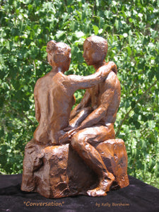 better view of man's left side and he speaks with his partner, ceramic sculpture set against the trees.