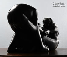 Load image into Gallery viewer, Her face looking at the man Helping Hands by Kelly Borsheim Couple Art Carved from a Marquina black marble, this sculpture depicts a man bending over forward to help a seated woman stand up.  Her hands reach up towards his bearded face, but it is the moment before she is close enough to reach him.  polished stone of final sculpture