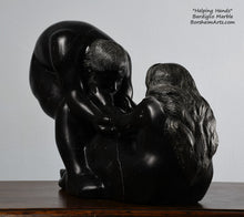 Load image into Gallery viewer, His face, hair and beard and her long hair flowing down the back Helping Hands by Kelly Borsheim Couple Art Carved from a black marble called Bardiglio from Italy, this sculpture depicts a man bending over forward to help a seated woman stand up.  Her hands reach up towards his bearded face, but it is the moment before she is close enough to reach him. 
