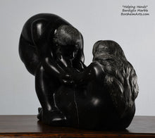 Load image into Gallery viewer, His face, hair and beard and her long hair flowing down the back Helping Hands by Kelly Borsheim Couple Art Carved from a black marble from Basque Country, this sculpture depicts a man bending over forward to help a seated woman stand up.  Her hands reach up towards his bearded face, but it is the moment before she is close enough to reach him. You see her long flowing hair and parts of the man's face.