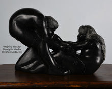 Load image into Gallery viewer, holes under arms in sculpture Helping Hands by Kelly Borsheim Couple Art Carved from a black marble called Bardiglio from Italy, this sculpture depicts a man bending over forward to help a seated woman stand up.  Her hands reach up towards his bearded face, but it is the moment before she is close enough to reach him. 
