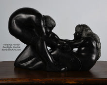 Load image into Gallery viewer, holes under arms in sculpture Helping Hands by Kelly Borsheim Couple Art Carved from a black marquina marble, this sculpture depicts a man bending over forward to help a seated woman stand up.  Her hands reach up towards his bearded face, but it is the moment before she is close enough to reach him. You may see the air spaces between the arms and legs of these figures.