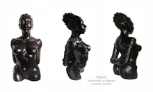 Load image into Gallery viewer, terra-cotta sculpture of a black woman with her hair pulled back into a large bun.  She stands tall and proud, her posture is slightly arched back with her arms folded together behind her, a beautiful physique
