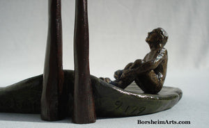 limited edition bronze sculpture detail of seated man.  signature on left, edition number to the right of the cattail stems.  bronze sculpture by Kelly Borsheim The Unwritten Future