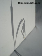 Load image into Gallery viewer, Shadow of the bronze sculpture The Unwritten Fugure shows a man hanging from cattails in a fantasy proportion. Sculpture by Kelly Borsheim