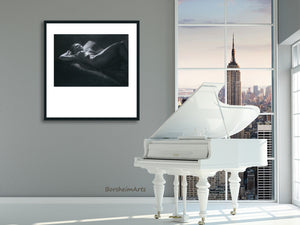 PRint of reclining nude woman thinking is framed in a simple thin line black frame and a white mat.  The mat is clearly cut so that it has a lot of white space below the art with top and sides being equal but very different from the bottom.  Shown here hung in a City loft apartment room with a white piano.
