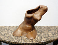 Terra-cotta hollow sculpture of a woman's torso sitting on a granite table, front view