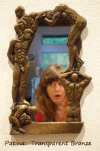 Load image into Gallery viewer, an asymmetrical frame of nude men for this small personal mirror.  shown here with the artist&#39;s face looking towards the nude men, patina is transparent bronze
