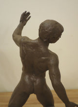 Load image into Gallery viewer, A brown patina on a bronze sculpture of a muscular male figure in a dynamic pose, shown from behind against a plain beige wall and light wood floor.
