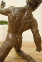 Load image into Gallery viewer, Close-up of a sculpted male figure from the back, showing muscular details and a matte earthy brown finish, standing on a light wood surface against a pale background.

