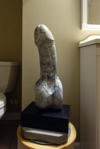 Contemporary Marble sculpture resembling a phallic shape on a pedestal in a bathroom setting.