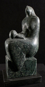 Dark green marble sculpture of a seated mother figure with squirming child on her lap as she looks to the sky.  sculpture on a black background