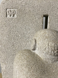 Close-up of a stone sculpture with a textured surface and the artist Vasily Fedorouk' signature logo carved into the limestone.