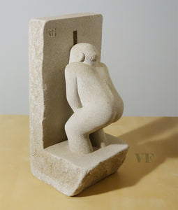 stone sculpture of a man pleasing himself while peeping through a hole in the wall
