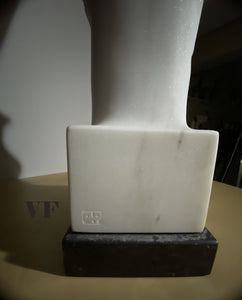 White marble sculpture on a dark stone  base showing the artist Vasily Fedorouk's mark as signature.