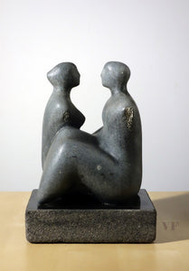 Abstract sculpture of two figures on a white background, female facing right, the male facing left
