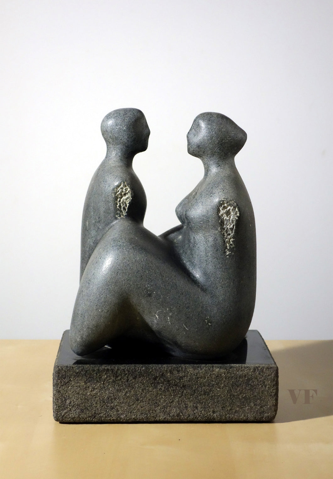 Gray stone sculpture of two figures on a white background