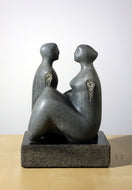 Gray stone sculpture of two figures on a white background