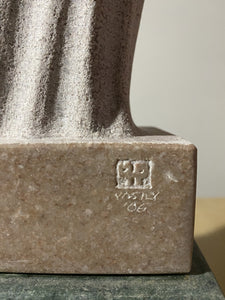 Close-up of a stone sculpture with a visible signature and year on a neutral background
