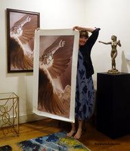 Charger l&#39;image dans la galerie, Artist Kelly Borsheim holds up the 50-inch tall print of her Icarus painting up against the length of her body.  The framed 40-inch tall version hangs on the wall behind her.  To the right is Kelly&#39;s sculpture &quot;Sirenetta&quot; aka The Little Mermaid nude woman sculpture.
