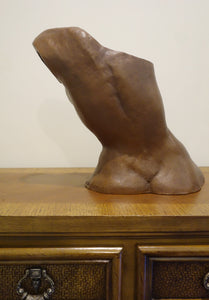 Back side of a leaning torso of a seated woman.  ceramic tabletop sculpture sitting on a dresser top.