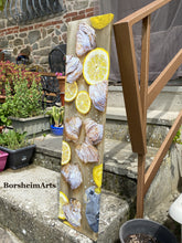 Load image into Gallery viewer, Lemons and pastries food painting shown standing up on the front stairs to the artist Kelly Borsheim&#39;s home.  Plants surround the stairs and the painting leans on the rail
