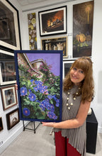 Laden Sie das Bild in den Galerie-Viewer, A woman with long light brown hair stands in an art gallery holding a framed painting of blue morning glory and bougainvillea flowers and a purple sky. The gallery walls are covered with other framed paintings by the same woman Kelly Borsheim.
