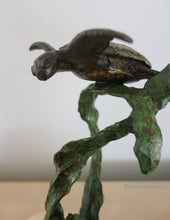 Charger l&#39;image dans la galerie, Bronze sculpture of a swimming sea turtle with limbs seeming to fly.  He is held up a branch of green kelp.
