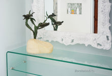 Charger l&#39;image dans la galerie, Glass shelf with decorative bronze and stone sculpture of swimming sea turtles, reflected in a white framed mirror on a modern bathroom wall.

