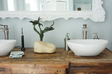 Charger l&#39;image dans la galerie, Bathroom vanity with two white sinks, a bronze sculpture of sea turtles, and toiletries on a wooden counter.
