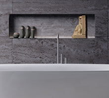 Cargar imagen en el visor de la galería, Modern bathroom with white tub area with gray tiles with a recessed shelf, a cream-colored stone decorative piece of sculpture, and a variety of bottles of soaps and shampoos.
