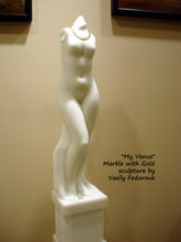 Cargar imagen en el visor de la galería, View of the left side of the vertical white marble sculpture of a standing female figure.  You may see here how the shoulder and the neck end (no arms or head).  You may also see some of the pedestal base, part of the same marble piece.  And the gold necklace around the neck.  Art by Vasily Fedorouk
