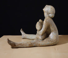 Load image into Gallery viewer, Profile view of Ceramic sculpture of a seated figure holding a pillow and looking to the sky with mouth open on a beige surface with a black background
